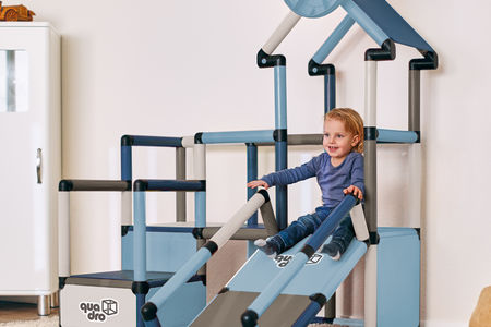 Child sliding on play house climbing frame